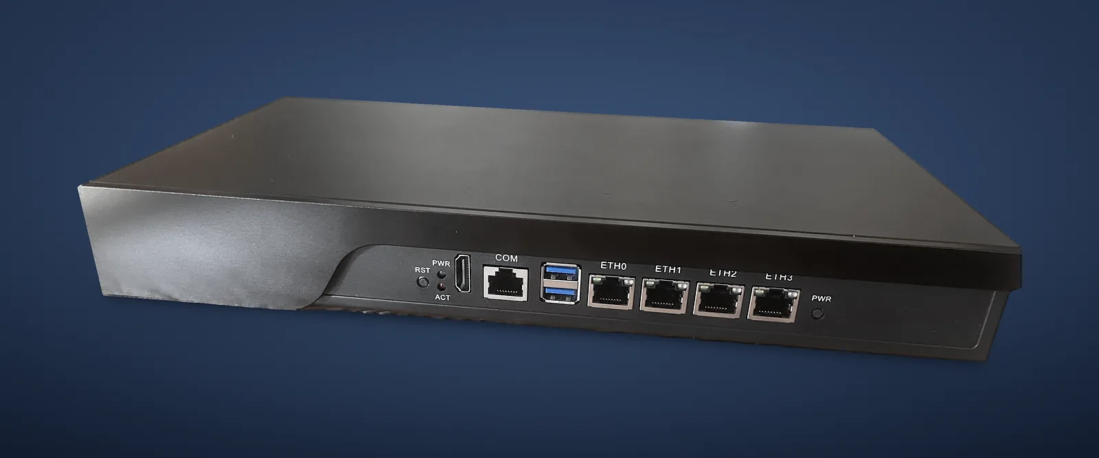 Echte foto van de IA-N-box in driekwartaanzicht van voren, op een neutrale achtergrond: zwarte behuizing, voorpaneel met resetknop, leds, HDMI, COM-consoleport, twee USB-ports, vier netwerkports ETH0 tot ETH3 en aan-uitknop.